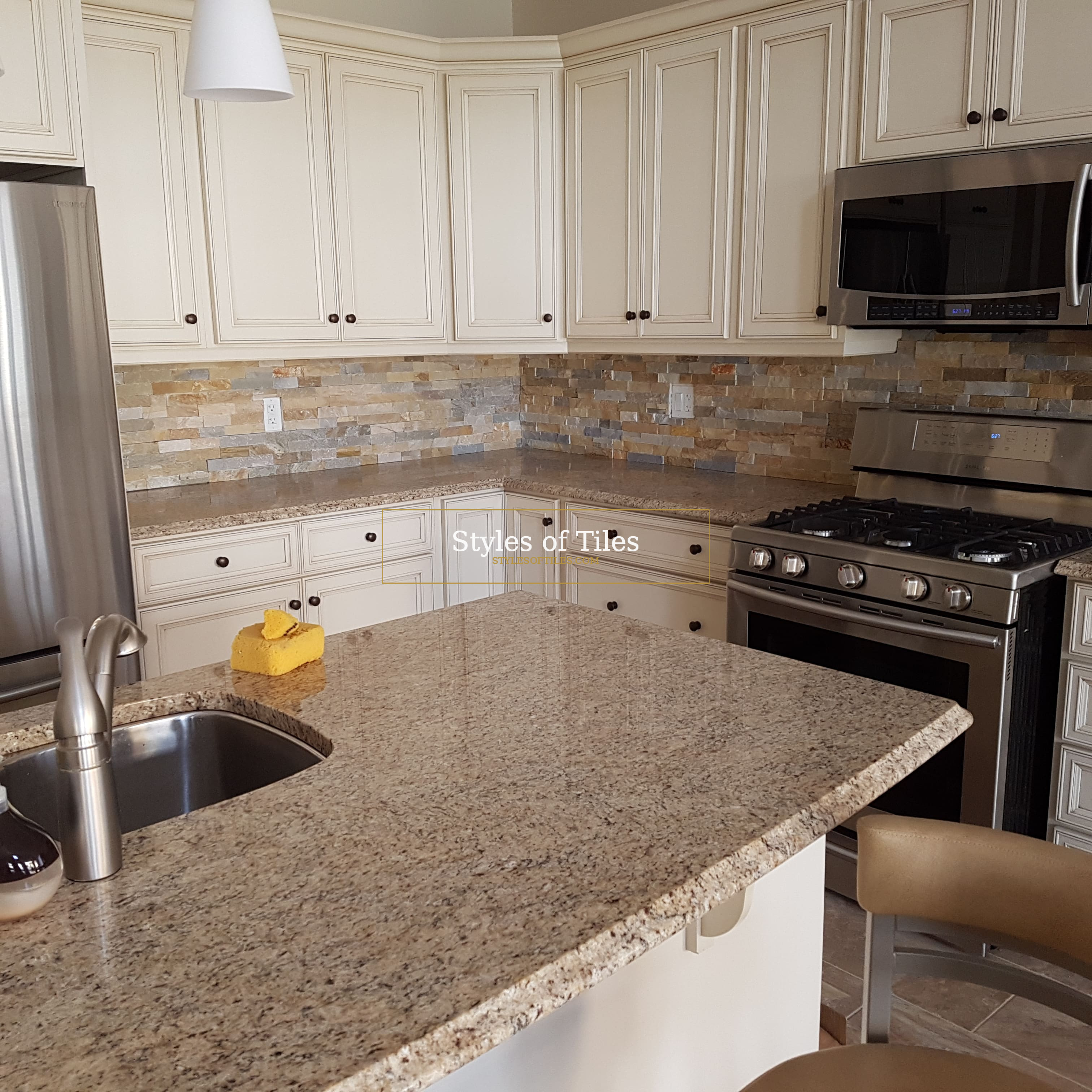 Multi-colour stacked slate backsplash behind a gas range in a kitchen with cream cabinets