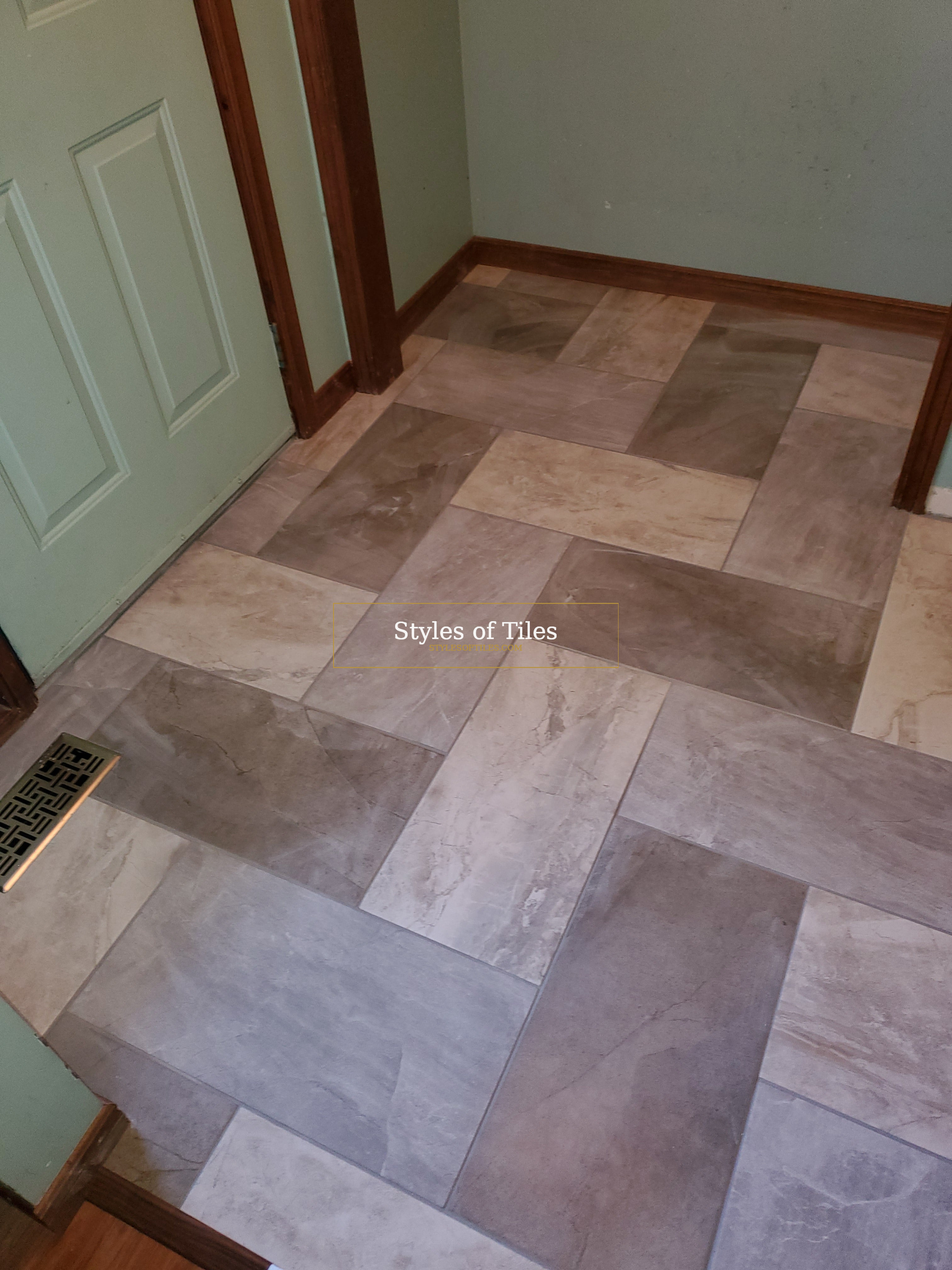 Entry floor in large grey rectangular tiles in two shades laid in a herringbone, with a floor register cut in