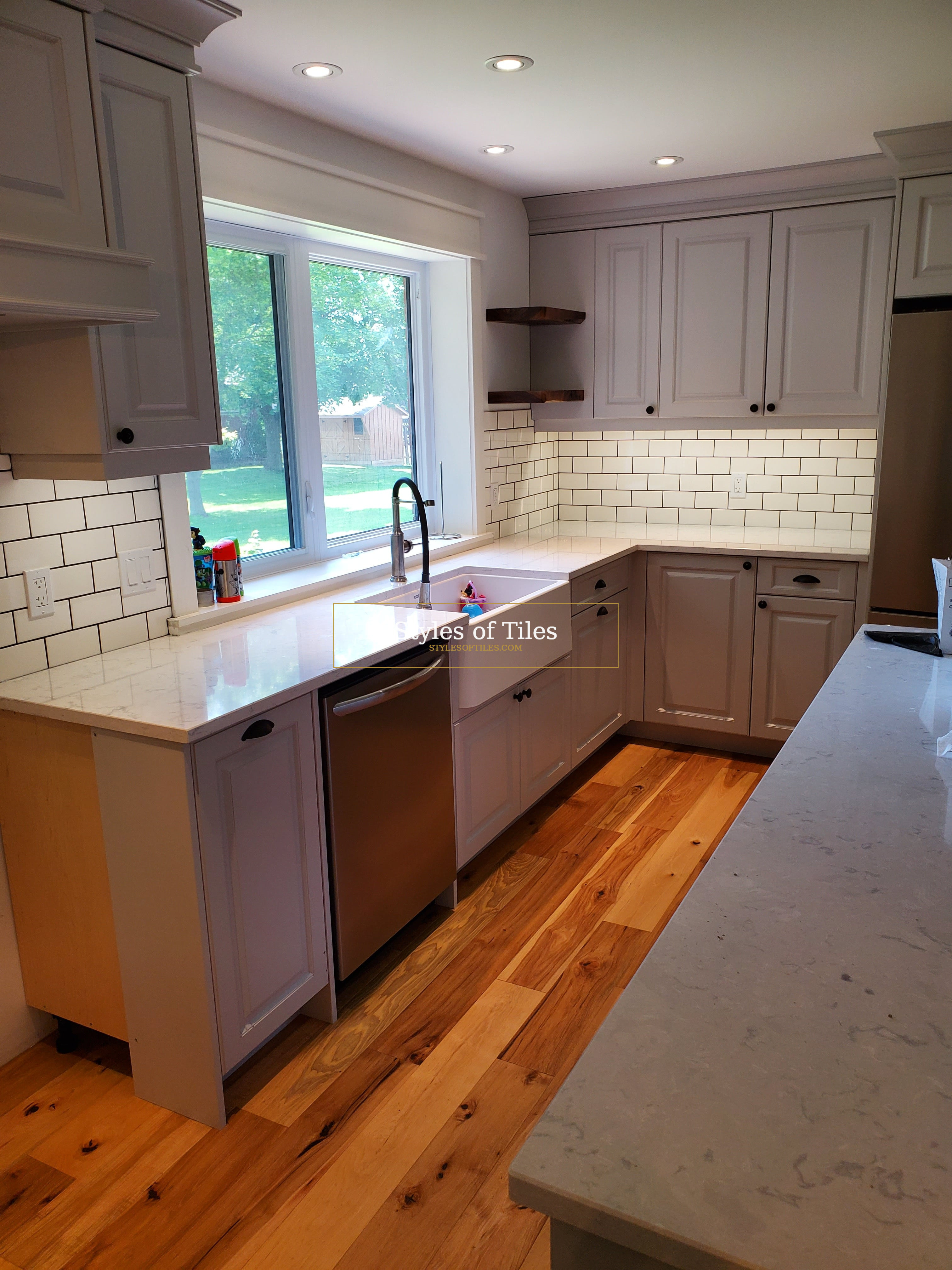 White subway tile backsplash with dark grout around a kitchen window and a farmhouse sink