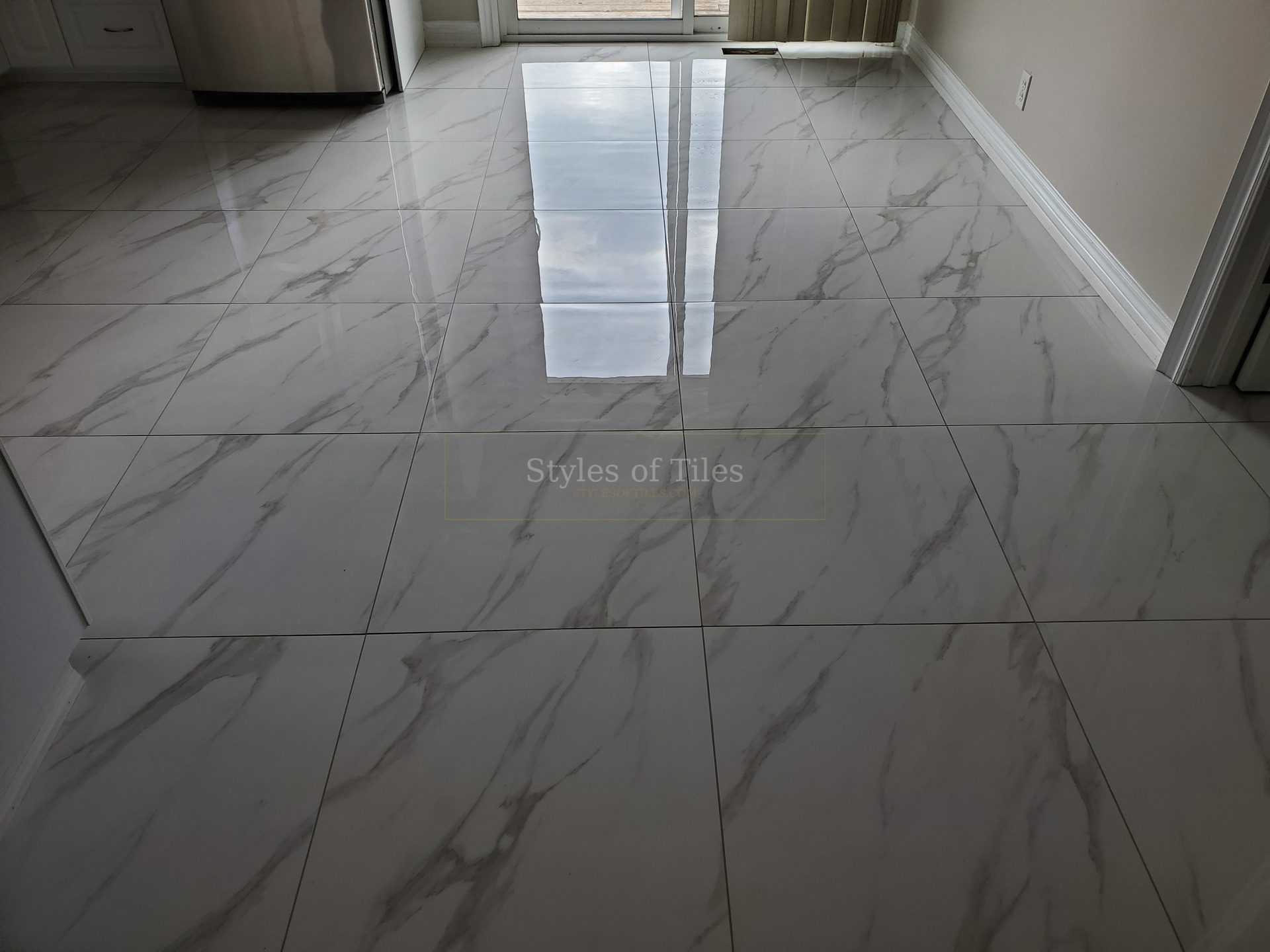 Polished marble-look large-format floor tile across an open room, with white baseboards on