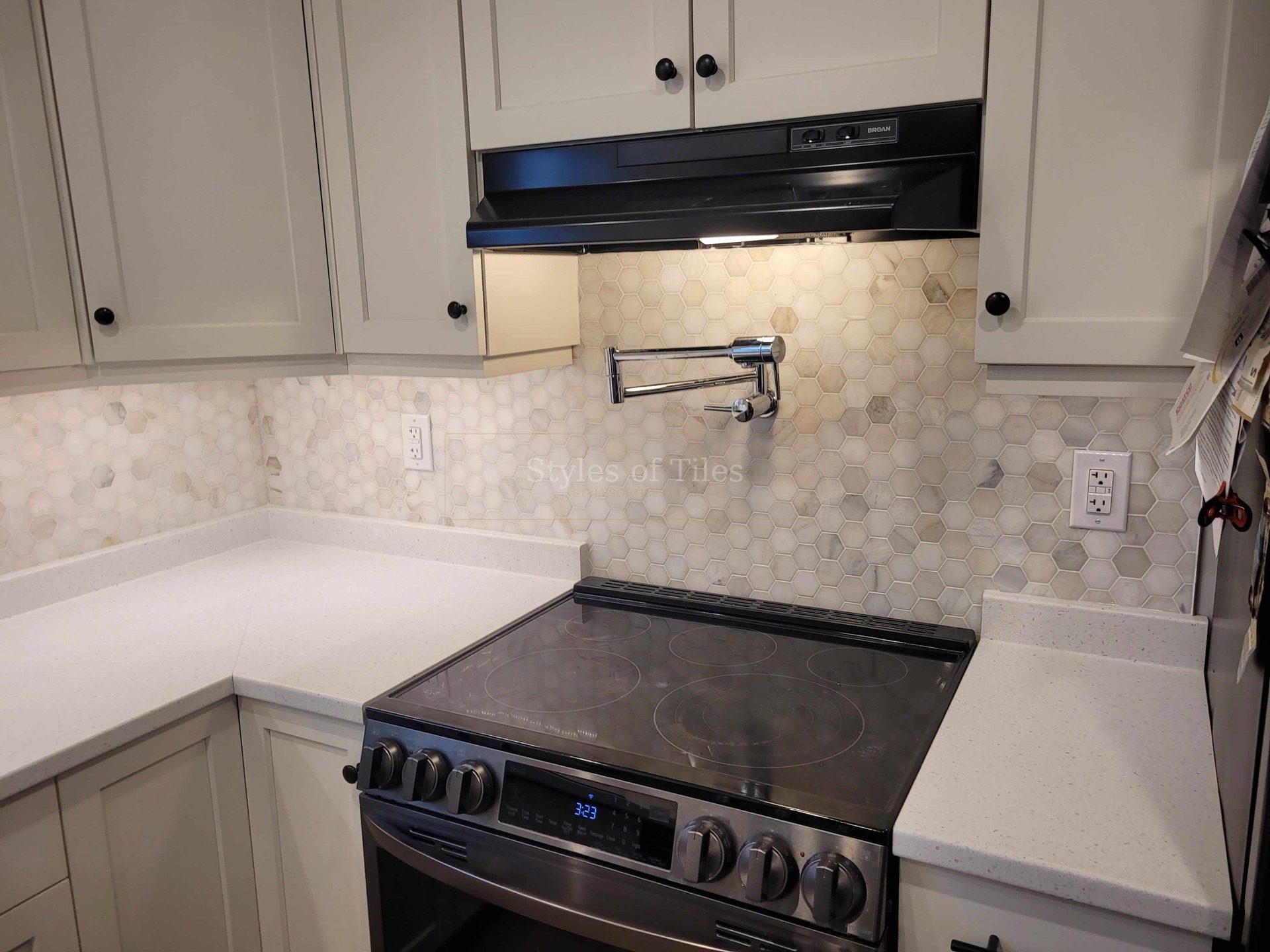 Marble hexagon mosaic backsplash with a pot filler tap behind an electric range