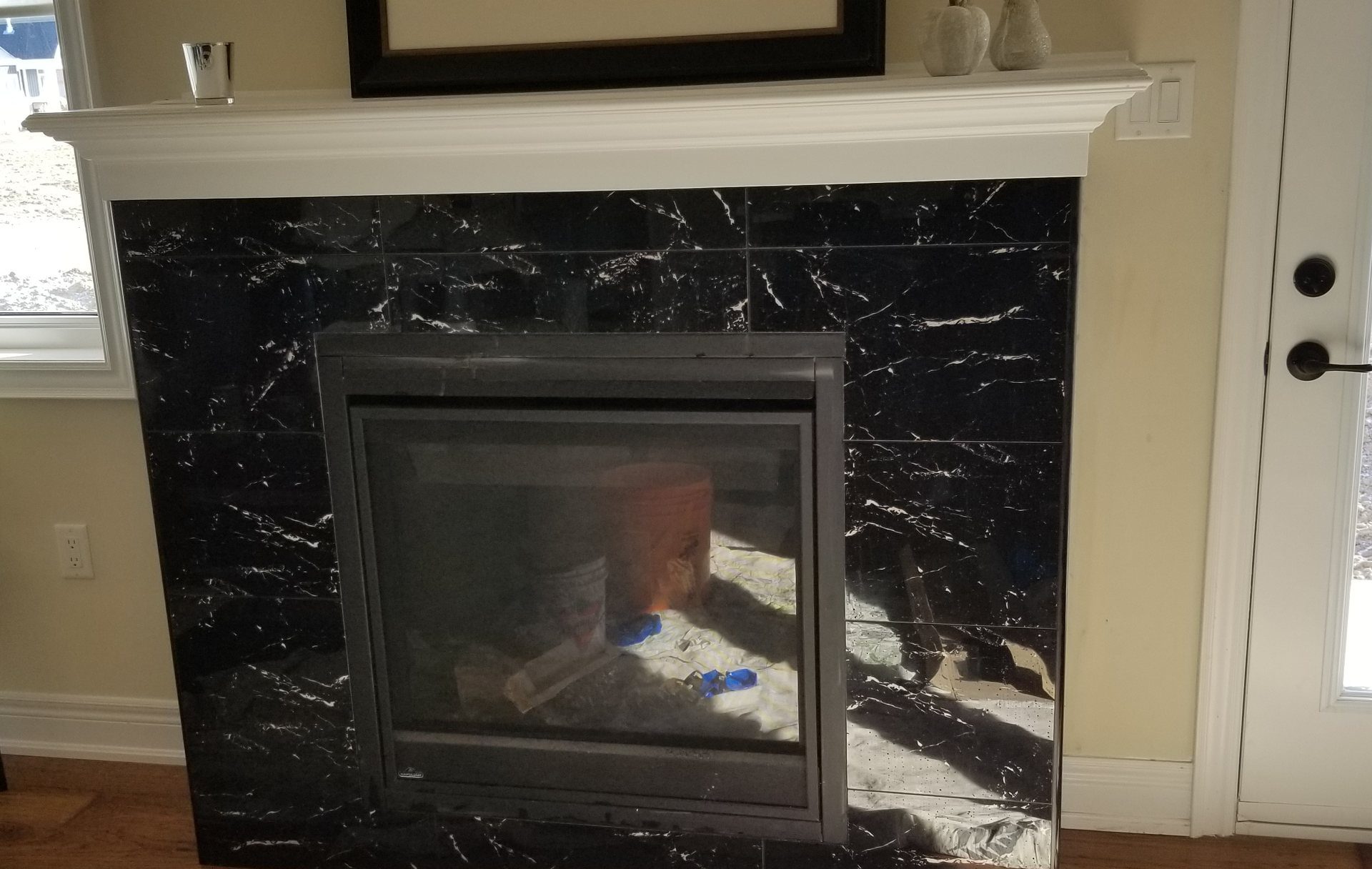 Black marble-look tile fireplace surround with white veining under a white mantel