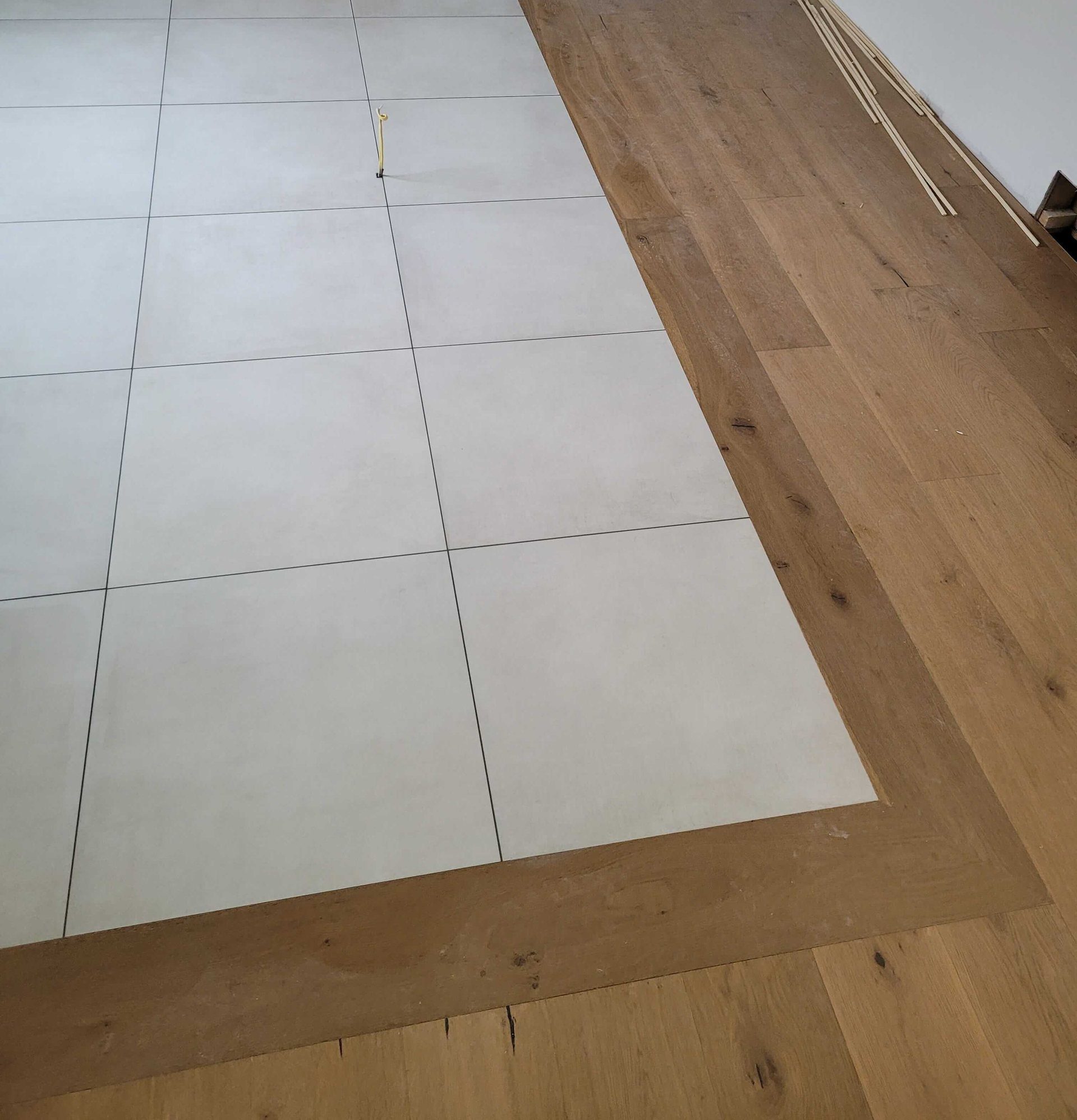Engineered oak hardwood laid as a mitred border around a large-format tile floor
