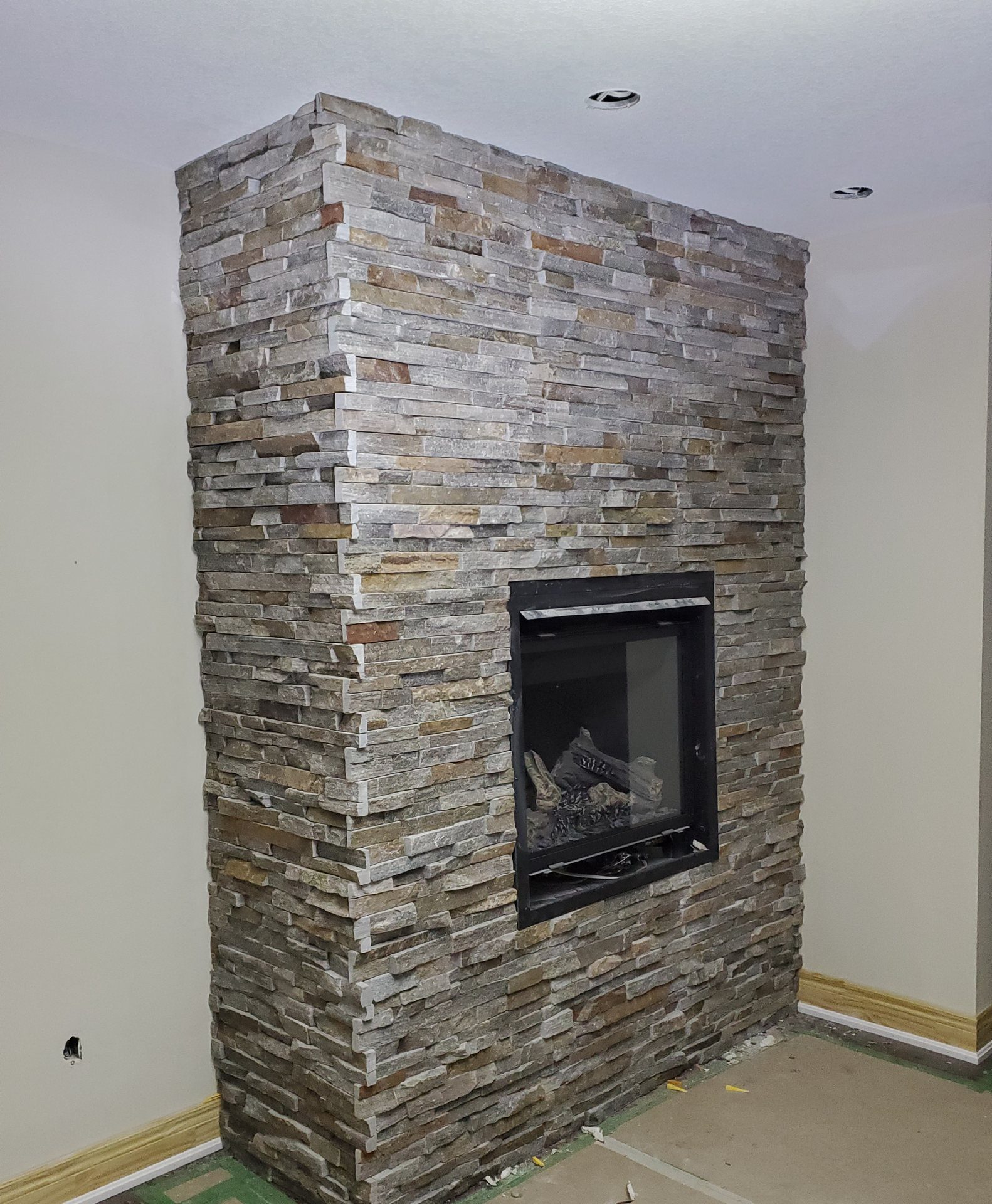 Side view of a stacked stone fireplace showing the stone wrapped around the corner