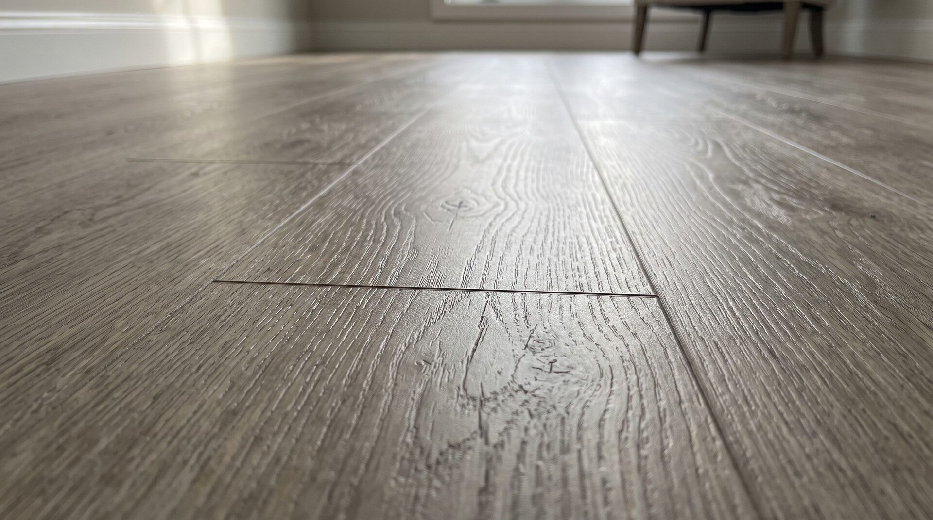 Close-up of grey vinyl plank flooring showing the wood-grain texture and the tight plank joints