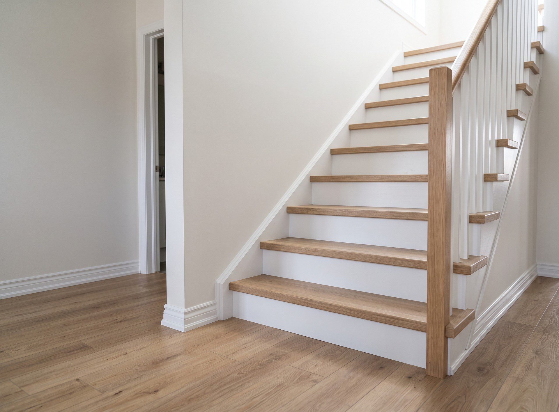 Light oak-look vinyl plank floor in a hallway, carried up a staircase with matching treads and white risers