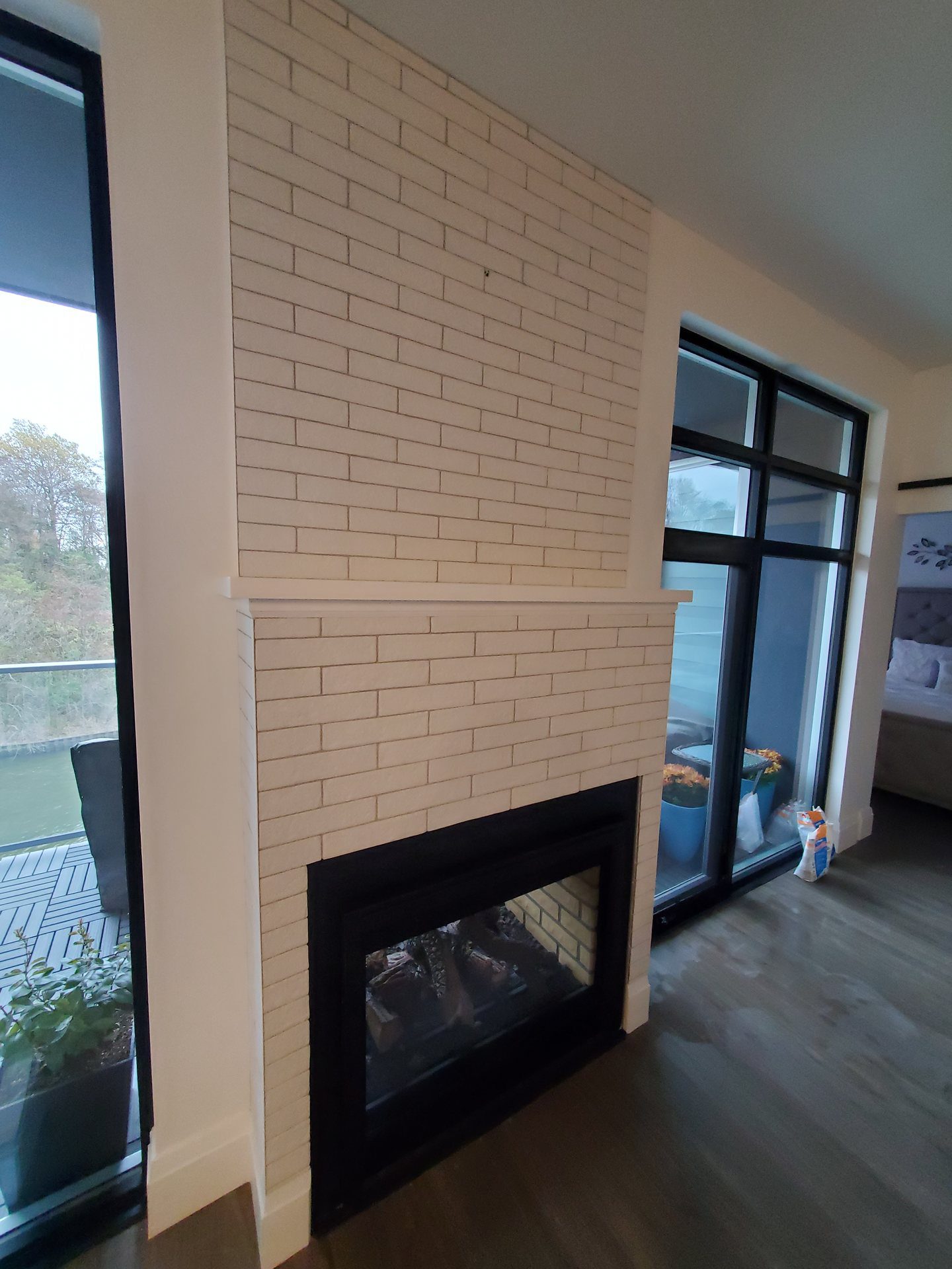 Fireplace tiled from floor to ceiling in white brick-look tile, with a tiled mantel ledge above the firebox