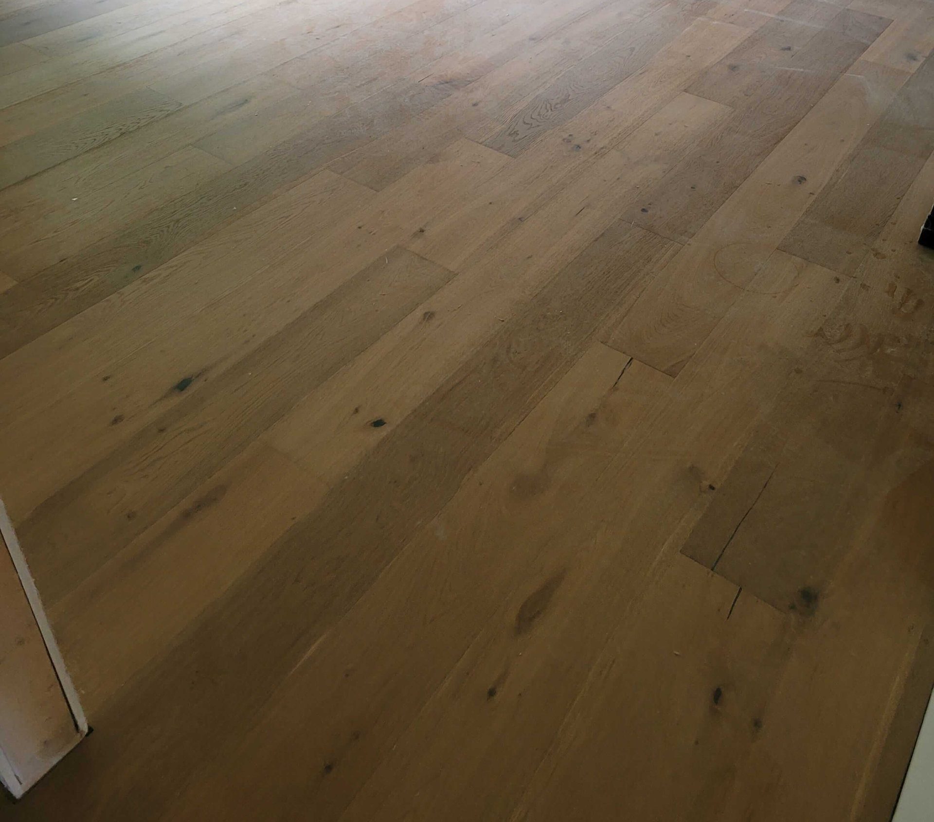 Wide-plank engineered oak hardwood floor running across a room, with staggered end joints
