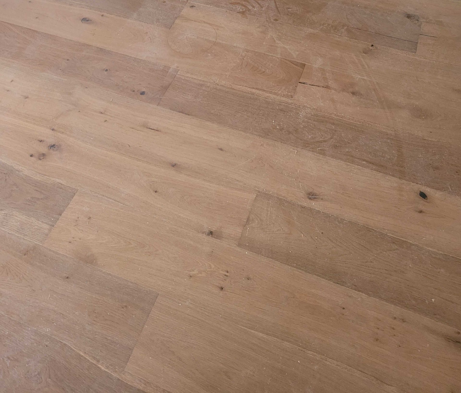 Close-up of wide-plank oak hardwood flooring showing the grain, the knots and the tight joints
